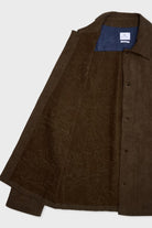 A dark brown textured overshirt with a subtle tonal floral jacquard pattern, shown open to reveal a blue inner lining and a white brand label inside the collar.