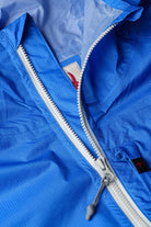 Close-up of a blue jacket with a zipper, showing brand logos.
