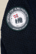Close-up of a dark navy textured fleece garment with a circular embroidered patch on the shoulder. The patch reads 'SPIRIT OF AMUNDSEN' and 'ANTARCTIC EXPO 2018' with a flag and silhouettes in the center.