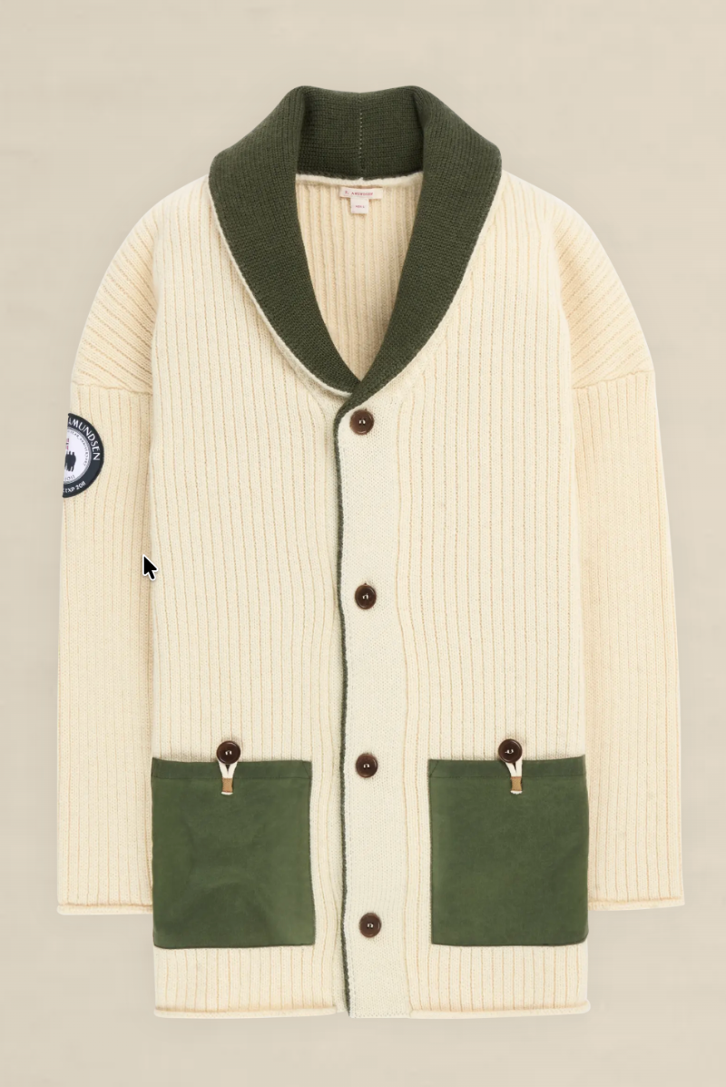 An off-white ribbed knit cardigan with an olive green shawl collar, green front pockets, and brown buttons, shown flat on a light beige background.