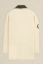 A cream-colored ribbed knit sweater shown from the back, featuring a dark olive green collar and a circular patch on the left sleeve, set against a light beige background.