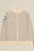 A cream-colored knit zip-up sweater with a dense black geometric pattern, featuring a mock neck, ribbed cuffs and hem, and decorative patches on the sleeves, displayed flat against a light beige background.