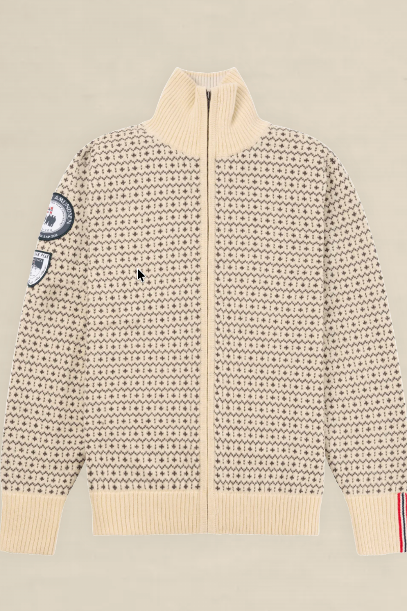 A cream-colored knit zip-up sweater with a dense black geometric pattern, featuring a mock neck, ribbed cuffs and hem, and decorative patches on the sleeves, displayed flat against a light beige background.