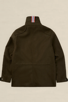 The back view of an olive green utility jacket with a high collar featuring a signature red, white, and blue striped ribbons detail, displayed on a neutral beige background.