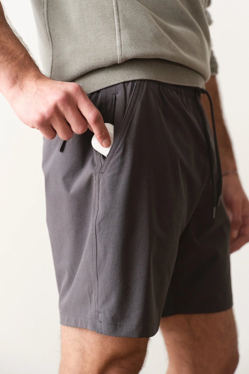 Person wearing gray shorts with a white background