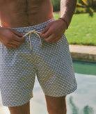 Person wearing patterned swim shorts by a poolside