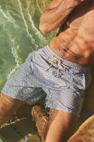 Person wearing blue patterned swim shorts in a natural setting