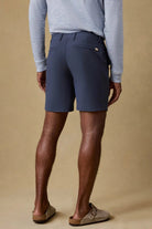 Person wearing navy shorts and a gray sweater on a beige background