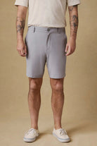 Person wearing gray shorts and white sneakers on a beige background