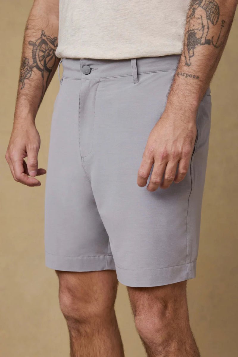 Person wearing light gray shorts on a beige background