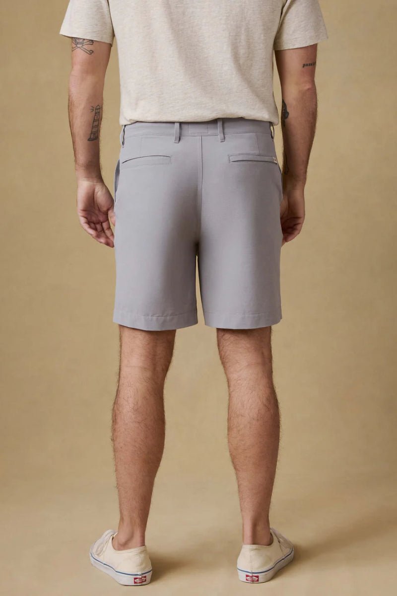 Person wearing gray shorts and a beige shirt on a beige background