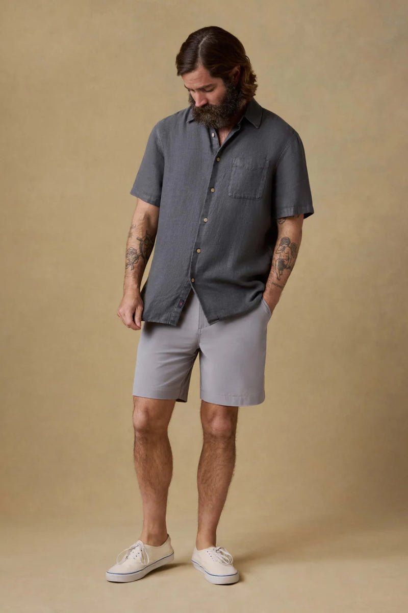 Man wearing a dark gray shirt and light gray shorts against a beige background