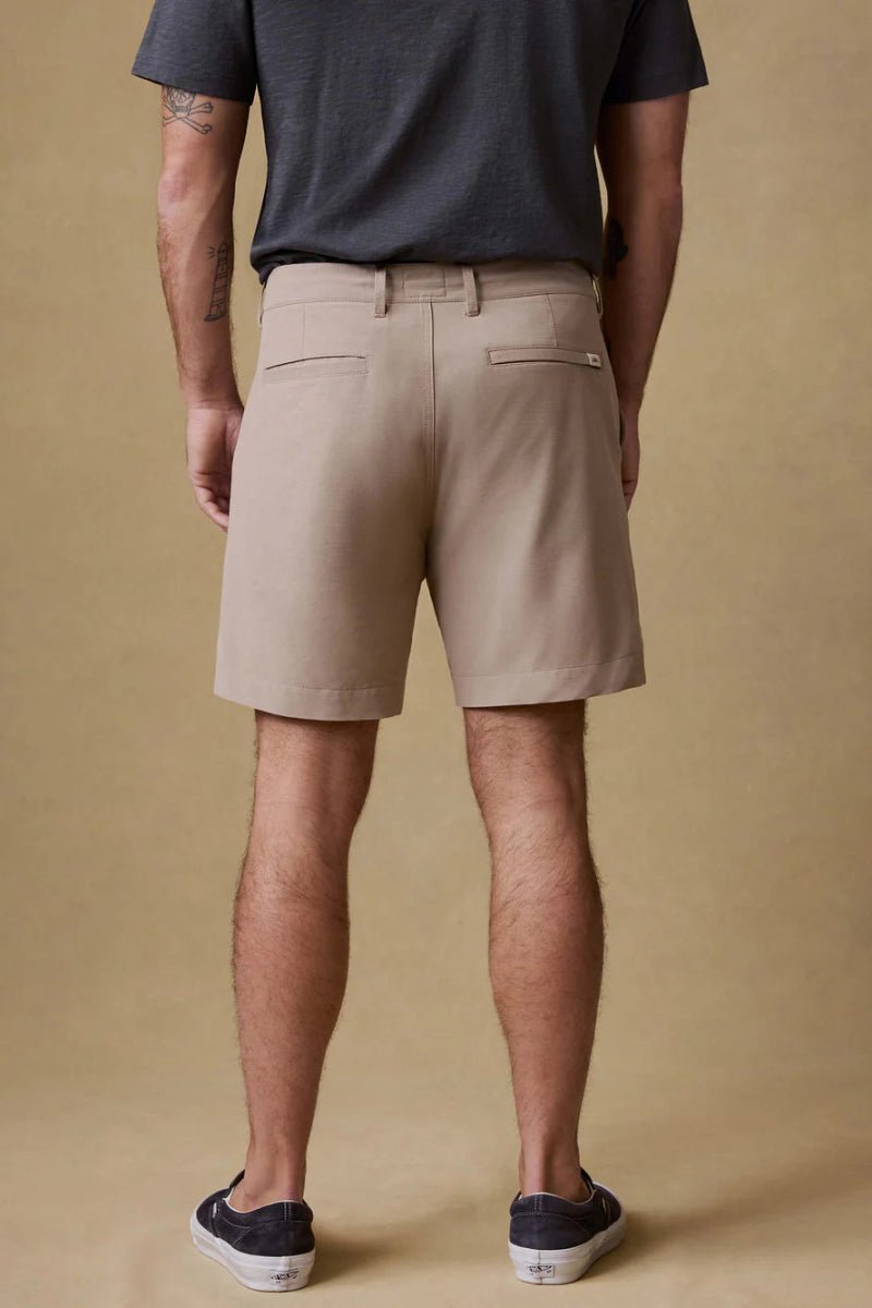 Person wearing beige shorts and a dark shirt on a beige background
