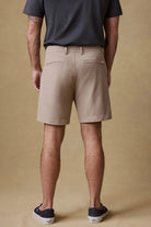 Person wearing beige shorts and a dark shirt on a beige background