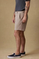 Man wearing beige shorts and black shoes on a beige background
