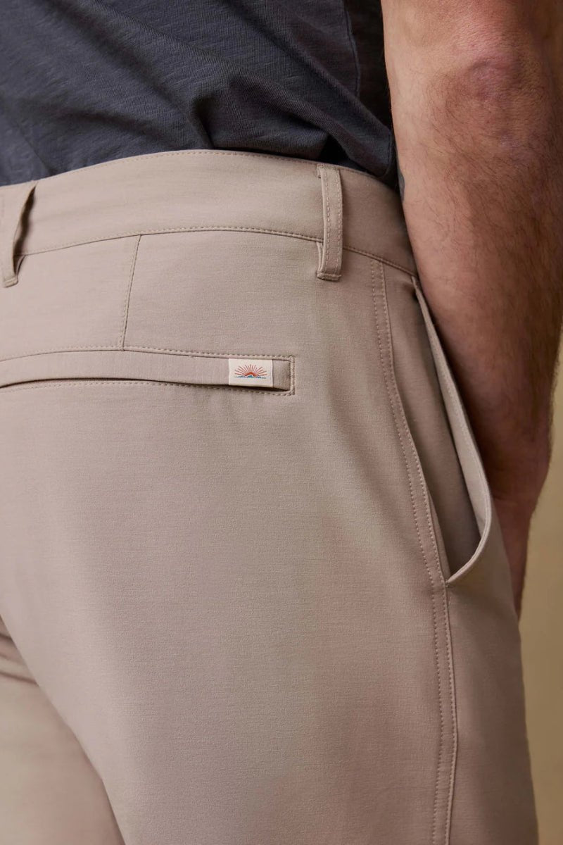 Beige pants with a brand logo on the pocket against a neutral background