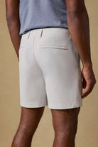 Person wearing light gray shorts and a blue shirt on a beige background