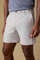Person wearing light-colored shorts and a blue shirt on a beige background