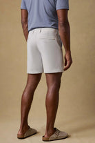 Person wearing light gray shorts and a blue shirt on a beige background