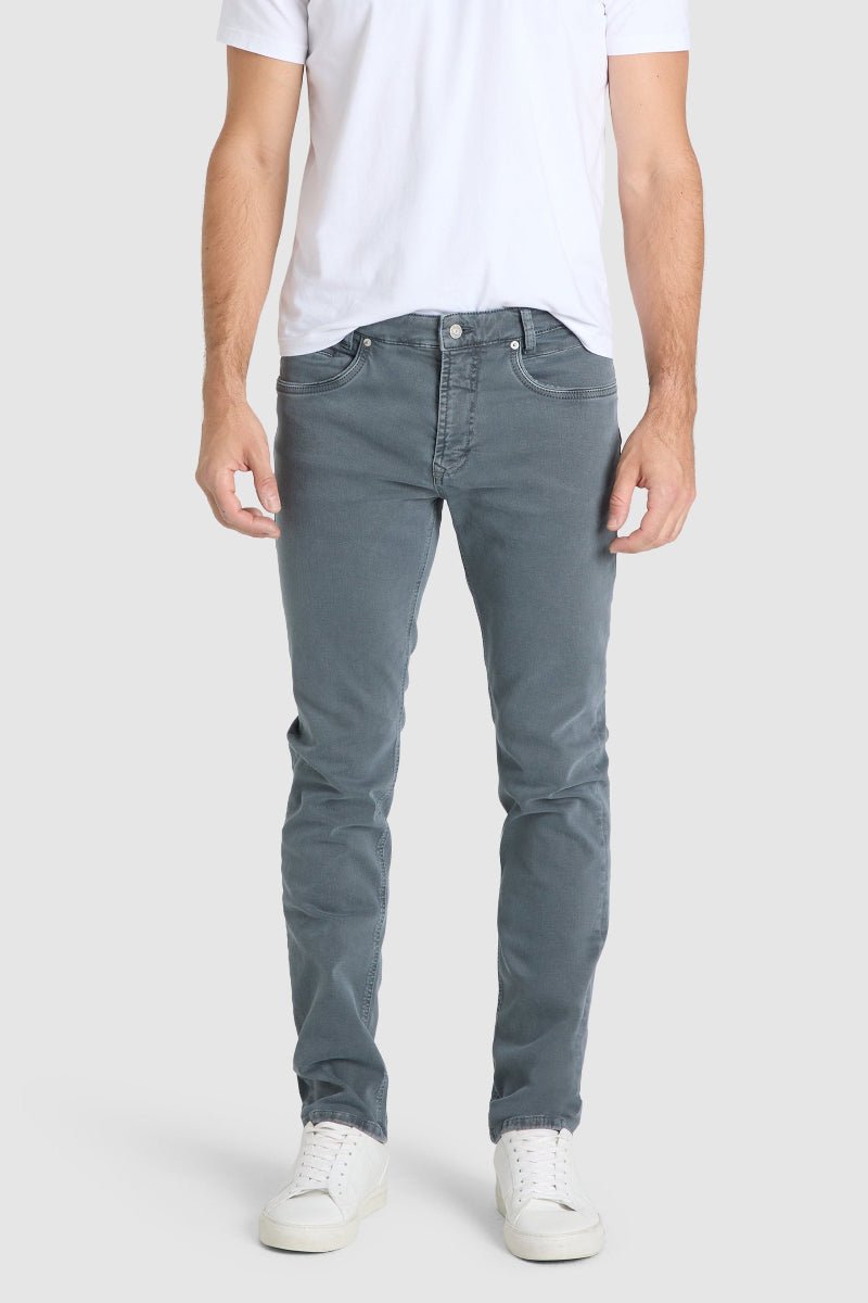 Person wearing gray jeans and a white t-shirt on a plain background