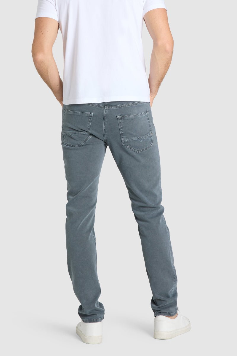 Person wearing gray jeans and a white t-shirt on a plain background