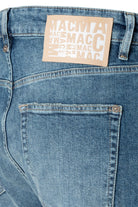 Close-up of blue jeans with a beige label on a white background