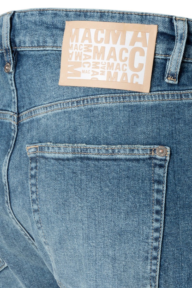 Close-up of blue jeans with a beige label on a white background