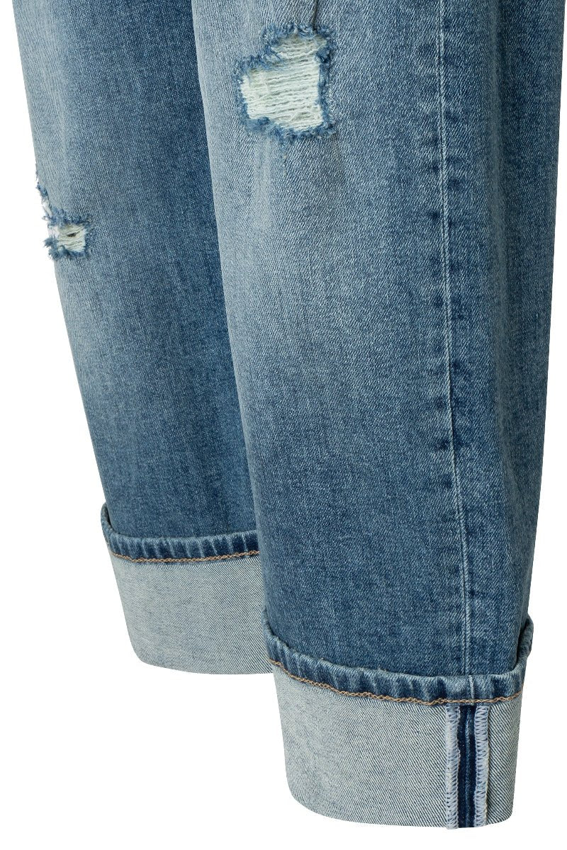 Close-up of blue denim jeans with a slight tear on a white background
