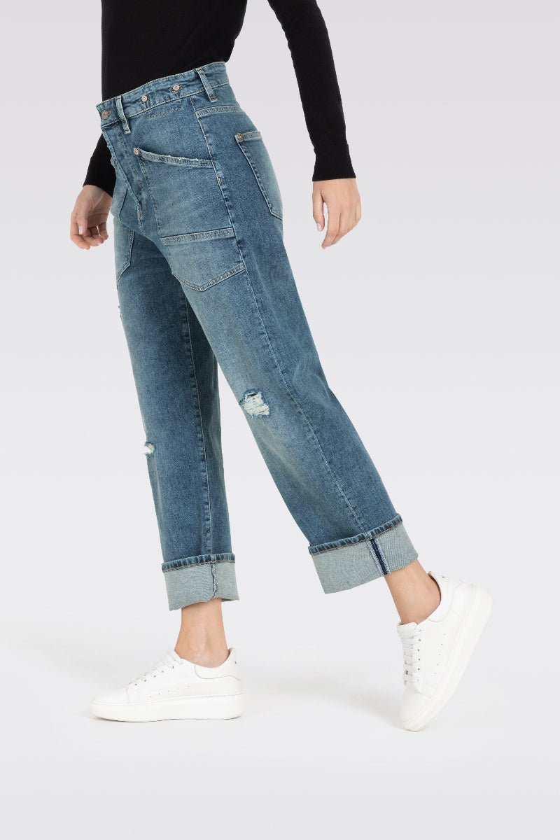 Person wearing blue jeans and white sneakers on a plain background