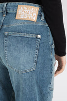 Blue jeans with a visible brand label on the back pocket against a white background