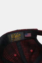Close-up of a red and black checkered jacket with a brand label on a white background