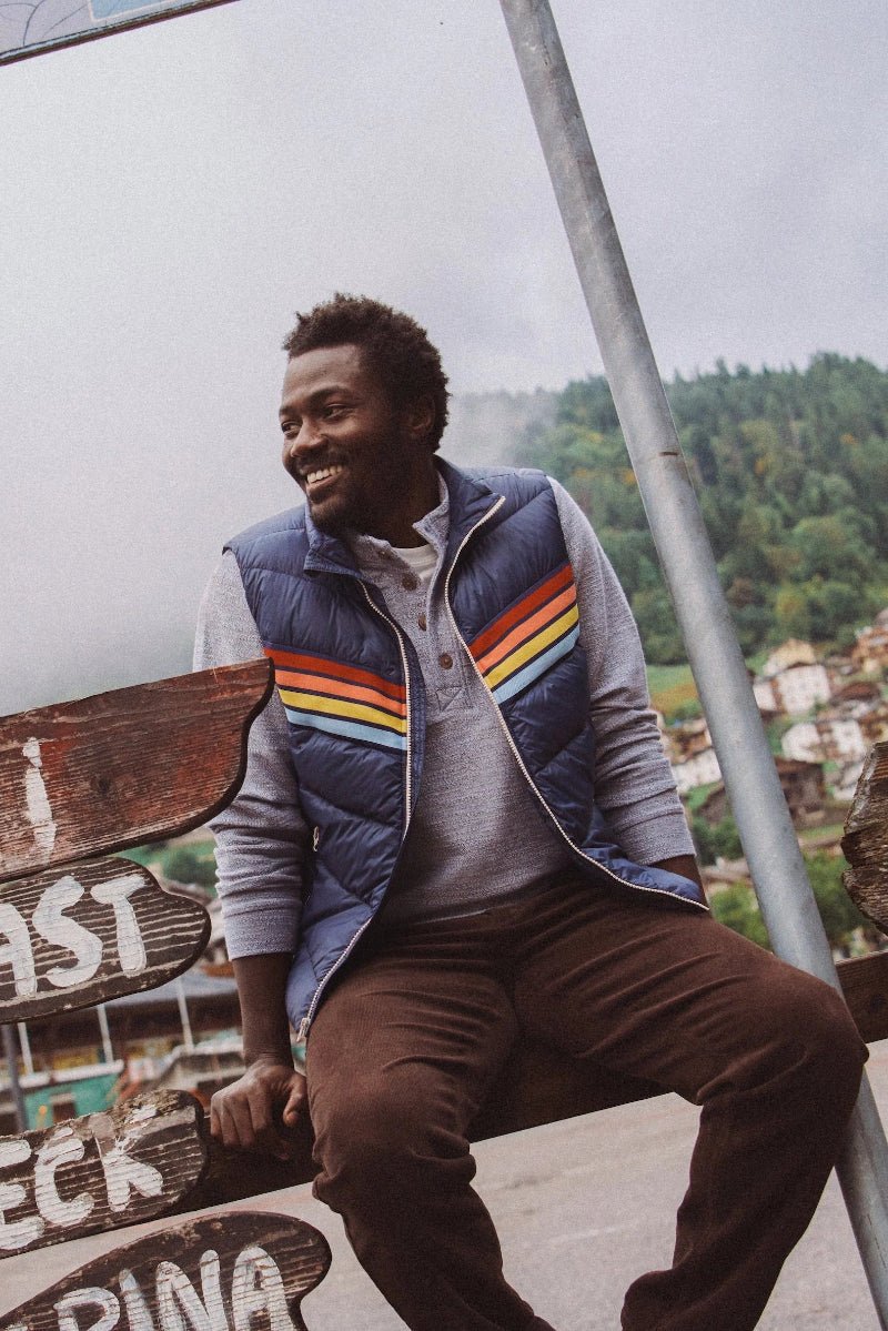 Man sitting on a wooden sign with a scenic background