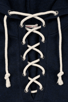 Close-up of a navy blue hooded sweatshirt with white laces threaded down the front and white drawstrings at the hood.