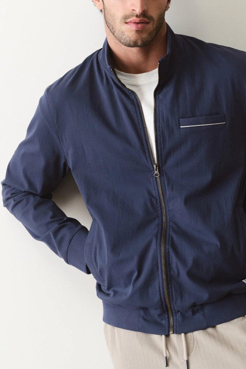 Man wearing a navy blue jacket against a plain background