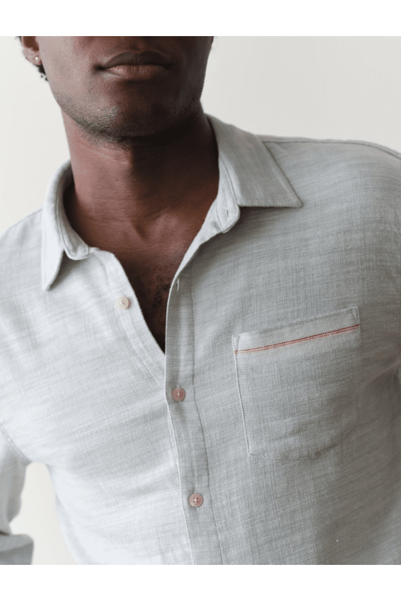 Man wearing a light gray linen shirt with a white collar against a neutral background