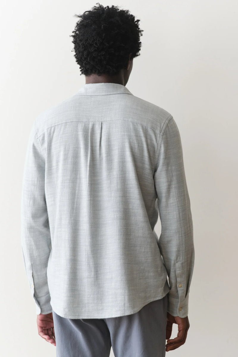 Person wearing a light gray long-sleeve shirt against a white background