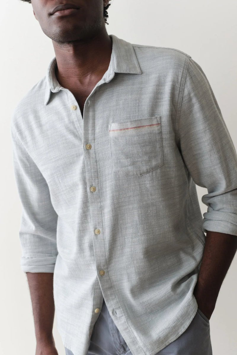 Man wearing a light gray button-up shirt with a plain background