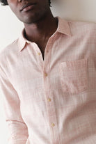 Person wearing a light pink checkered shirt against a neutral background