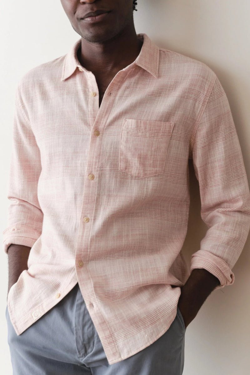 Person wearing a light pink checkered shirt against a white background