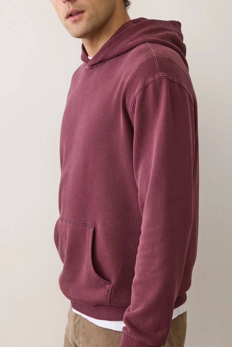 Maroon hoodie worn by a person on a plain background