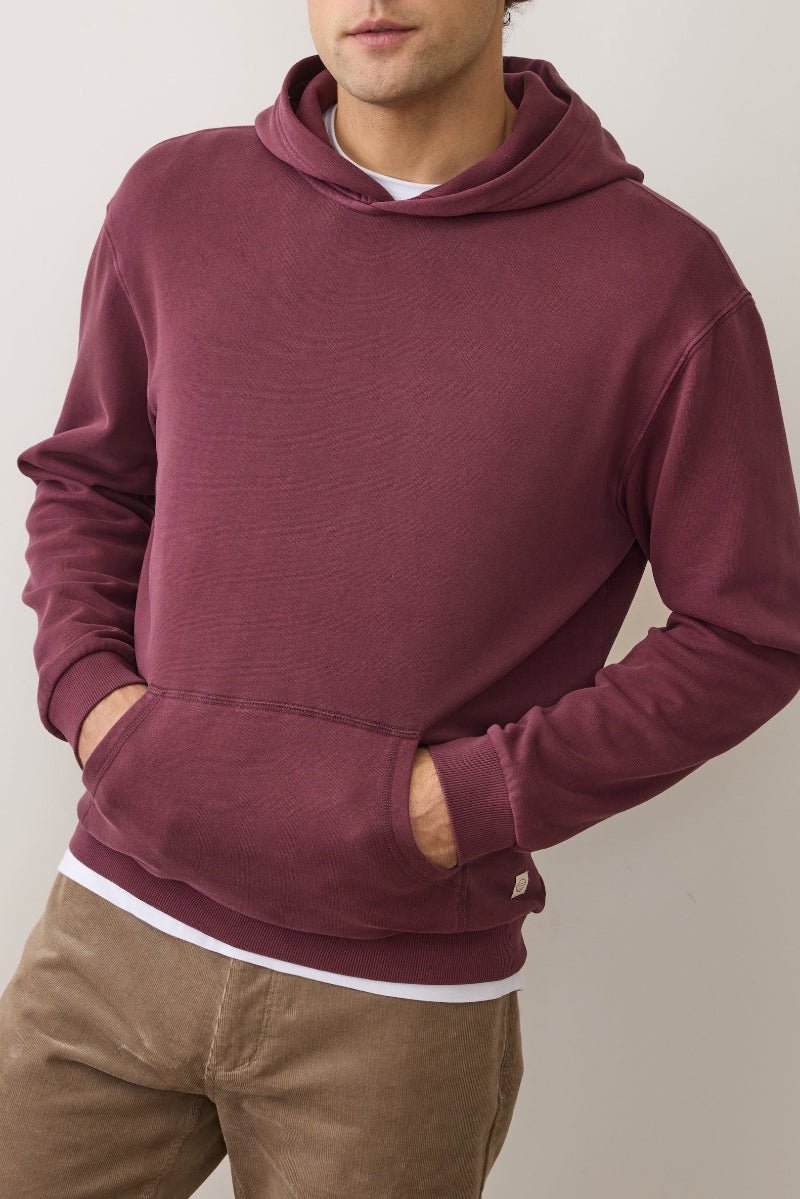 Person wearing a maroon hoodie with a neutral background