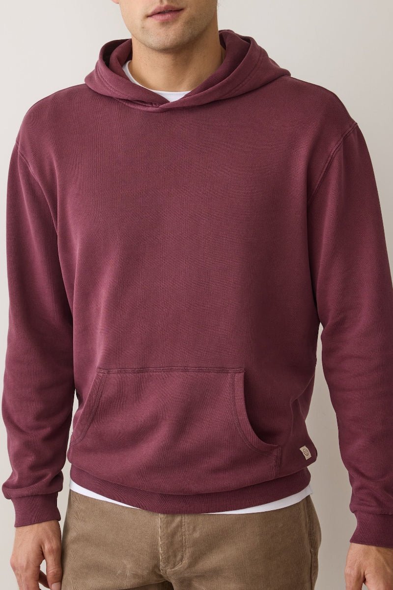 Maroon hoodie worn by a person on a plain background