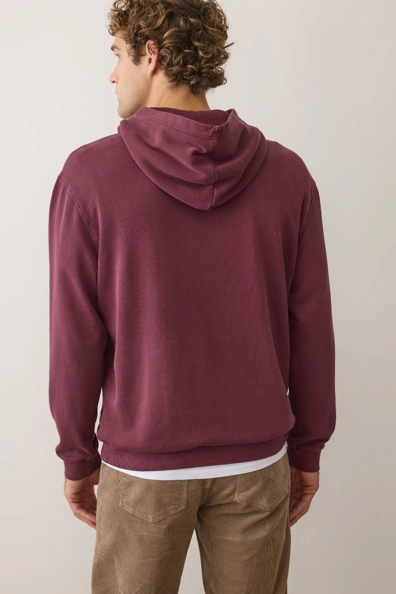 Man wearing a maroon hoodie from behind on a plain background