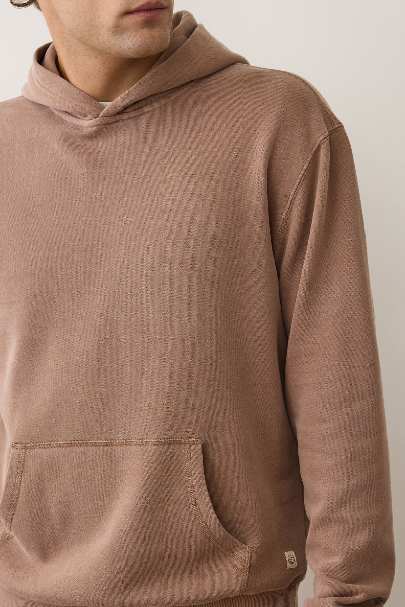 Brown hoodie worn by a person on a plain background