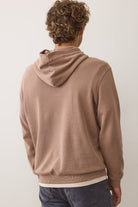 Person wearing a brown hoodie from behind on a plain background