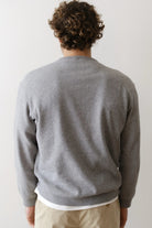 Person wearing a gray sweater from behind on a plain background