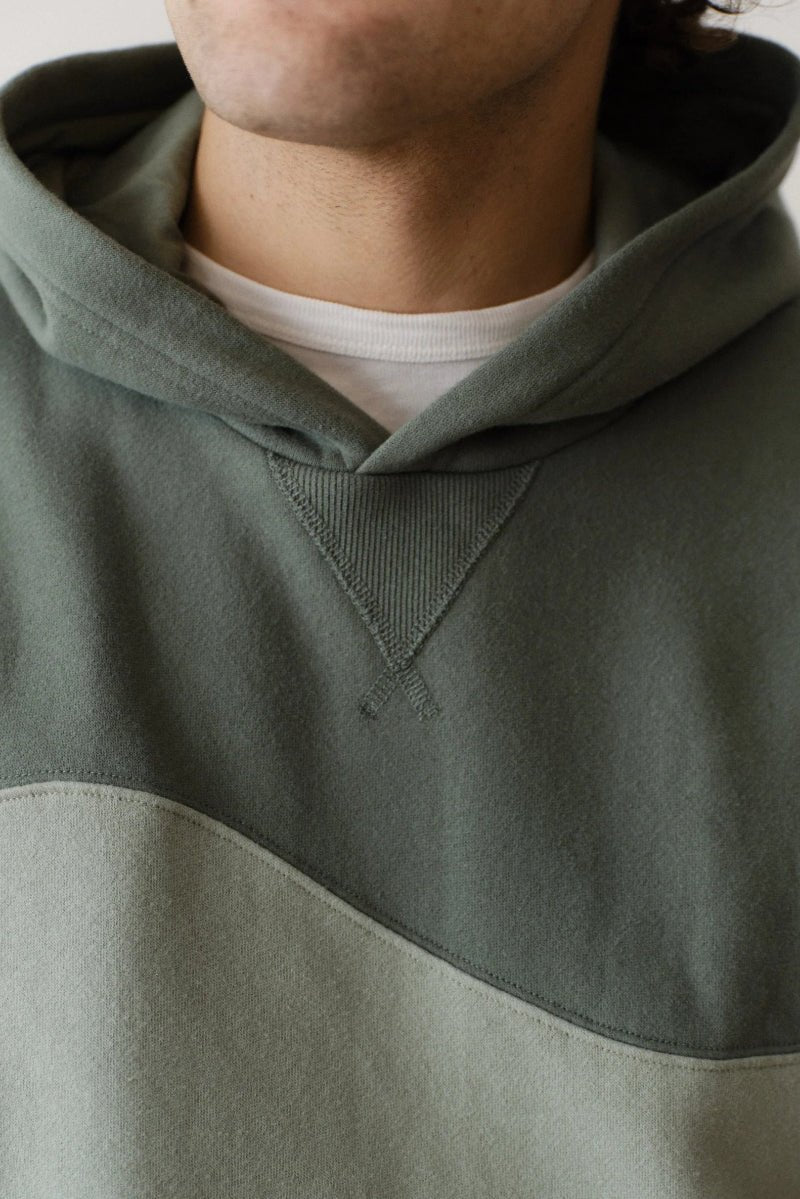 Person wearing a green hooded sweatshirt with a neutral background