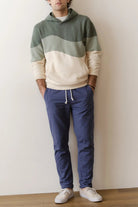 Person wearing a color-blocked hoodie and blue pants against a plain background