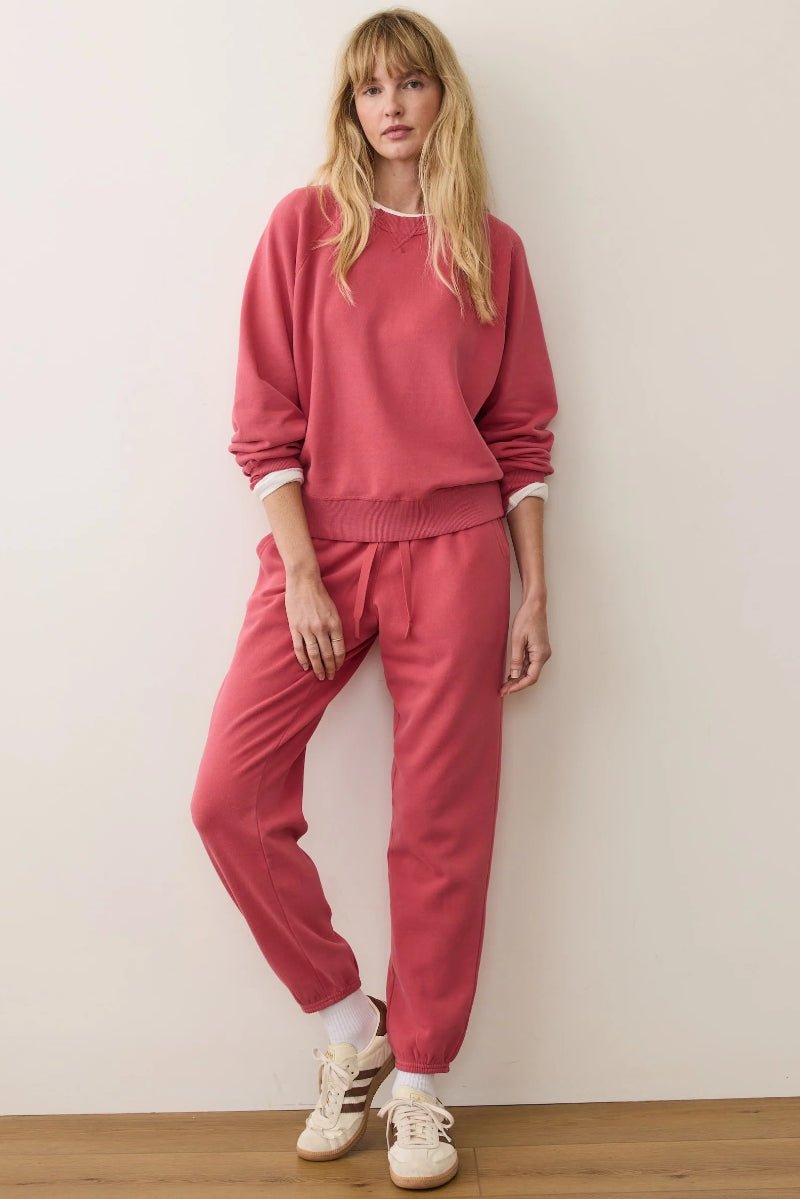 Woman wearing a pink tracksuit against a white wall