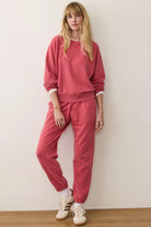 Woman wearing a pink tracksuit against a white wall
